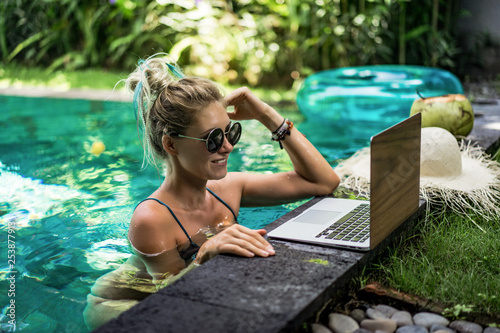 Woman working on laptop in the pool