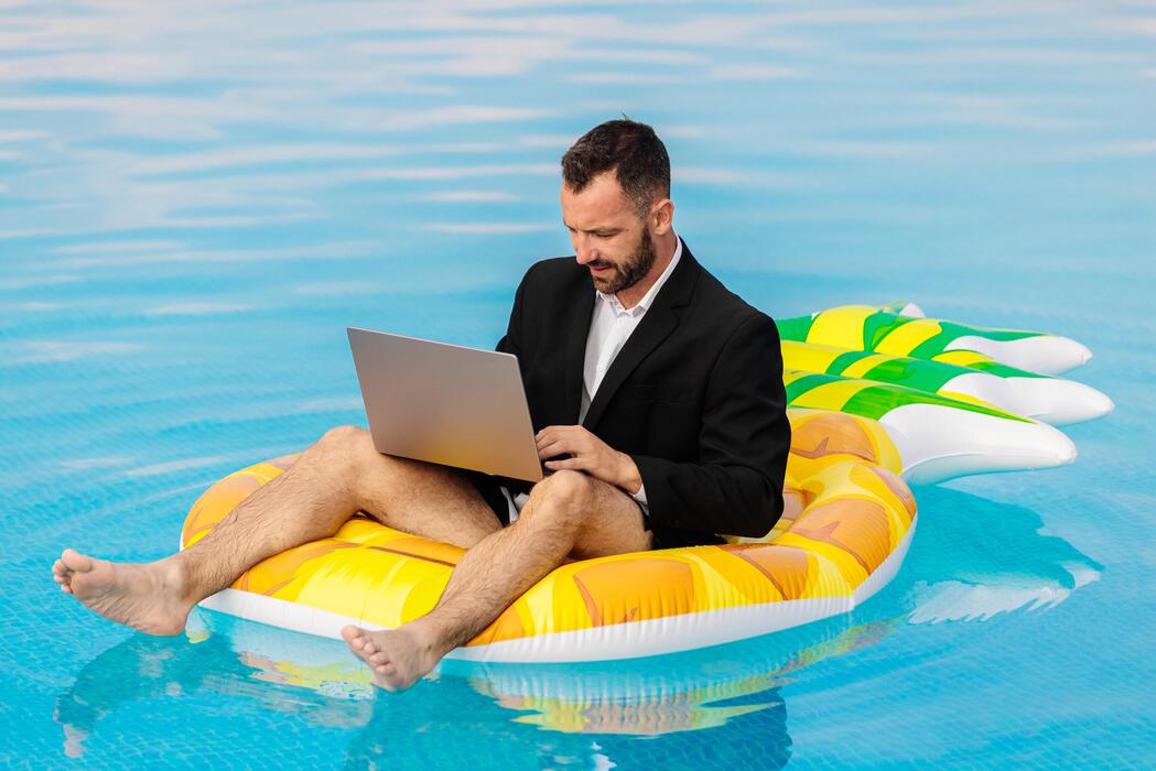 Man working on laptop on a pool float